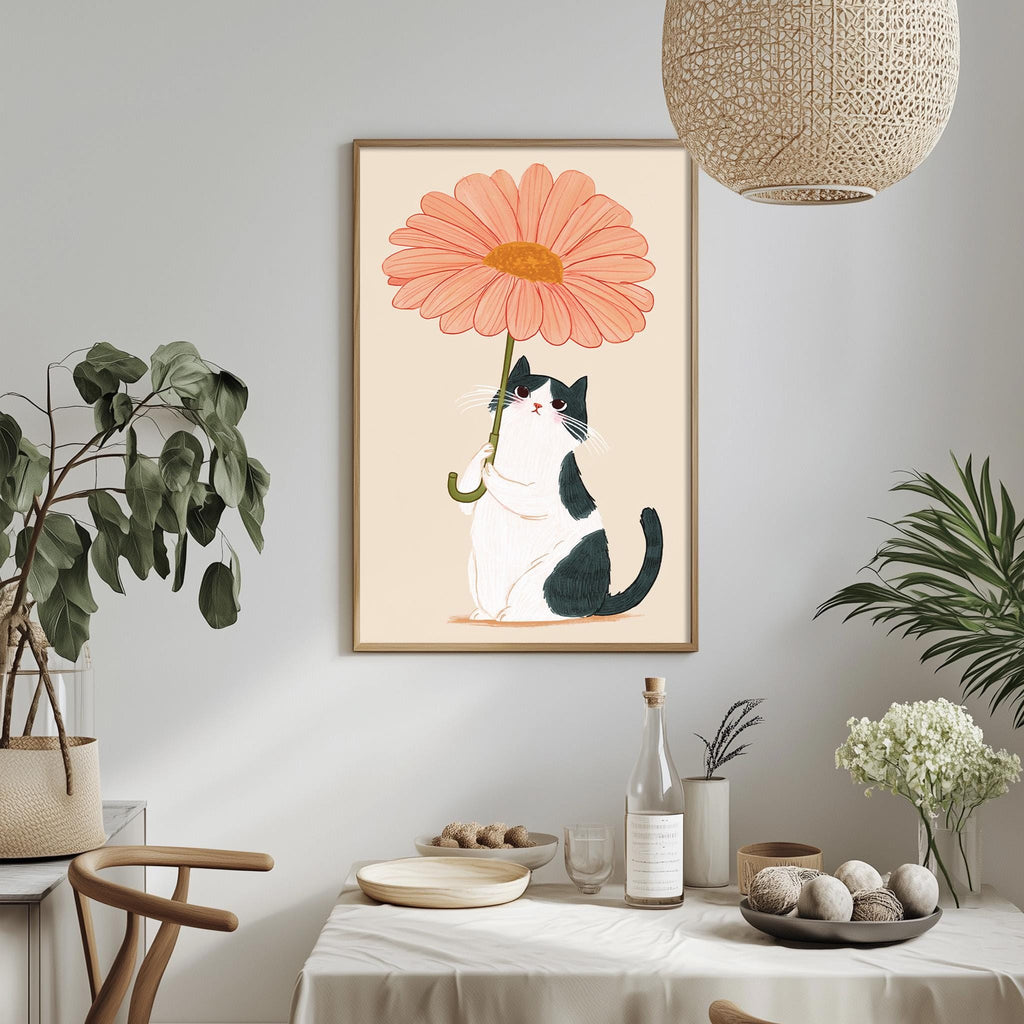 a framed illustration of a cat holding a large pink flower, which is hanging on a wall above a dining table.