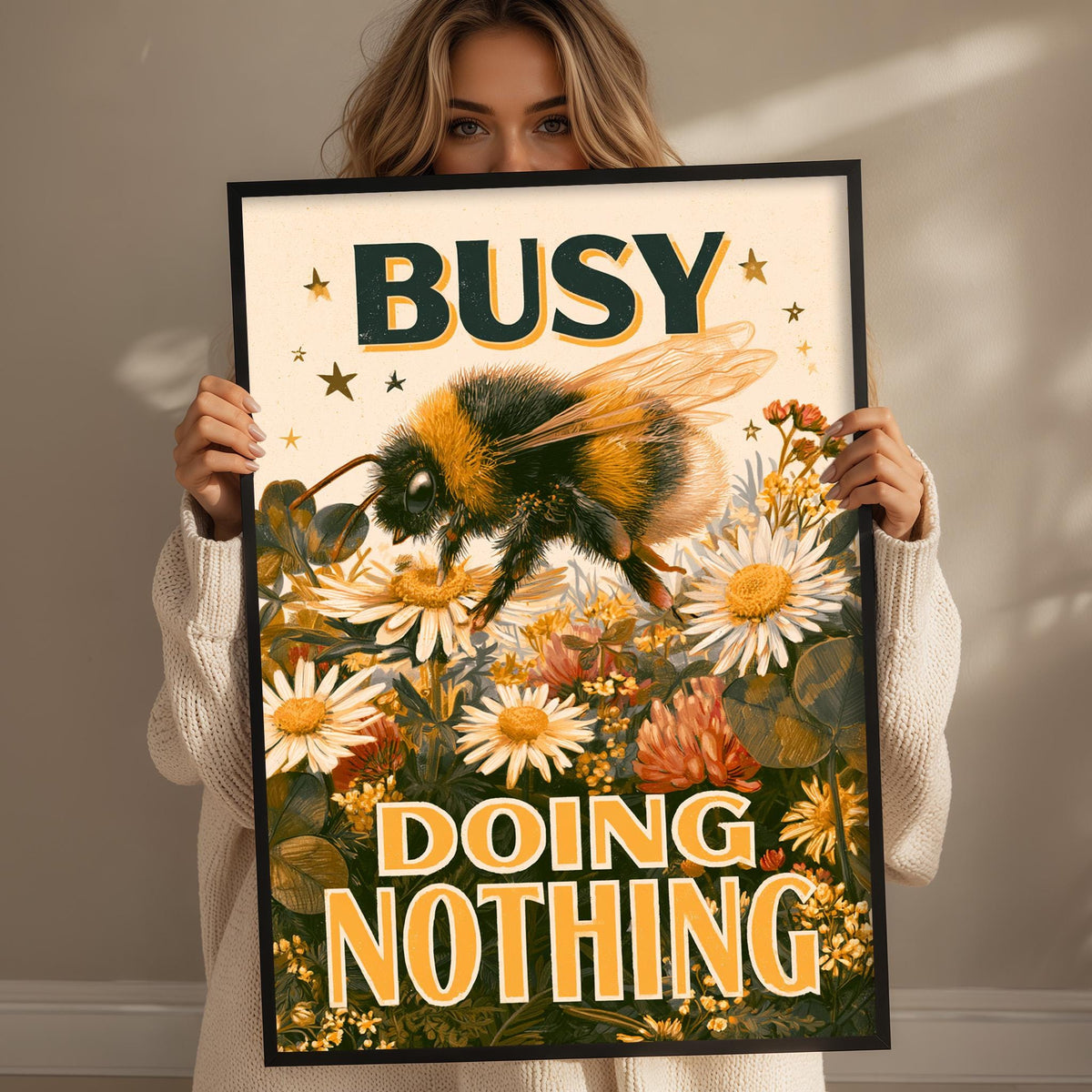 A woman holding a framed poster with a bee and flowers on it, with the text "BUSY DOING NOTHING" written on it.