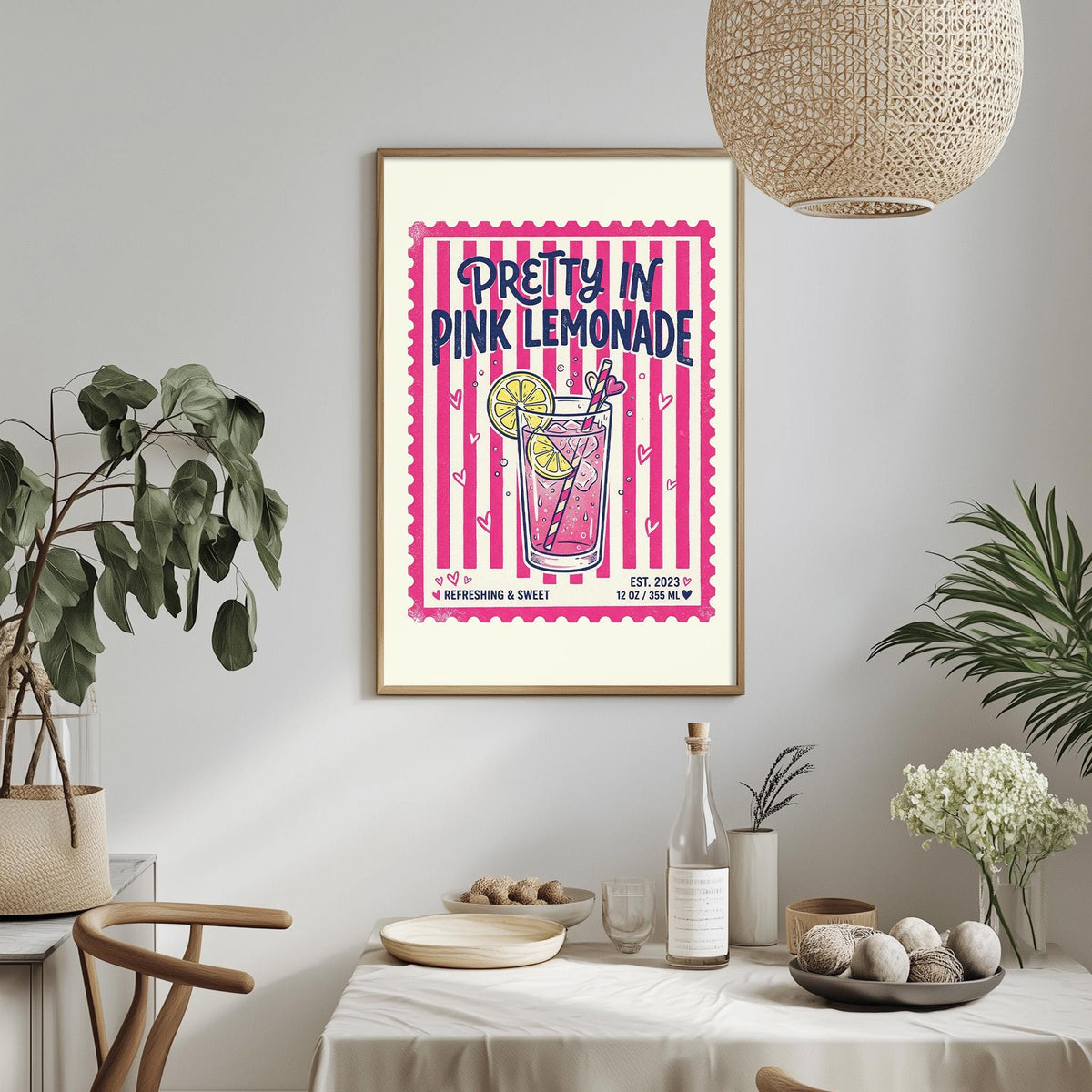 a framed poster of a pink lemonade drink hanging on a wall, with a dining table and chairs in the foreground.