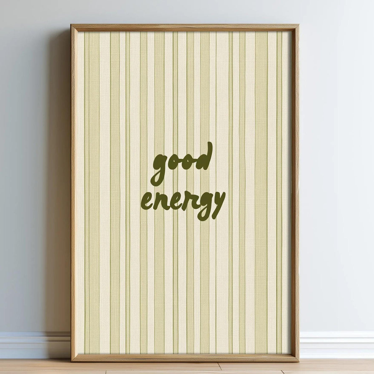 A framed poster with a striped background and the text "good energy" printed on it.