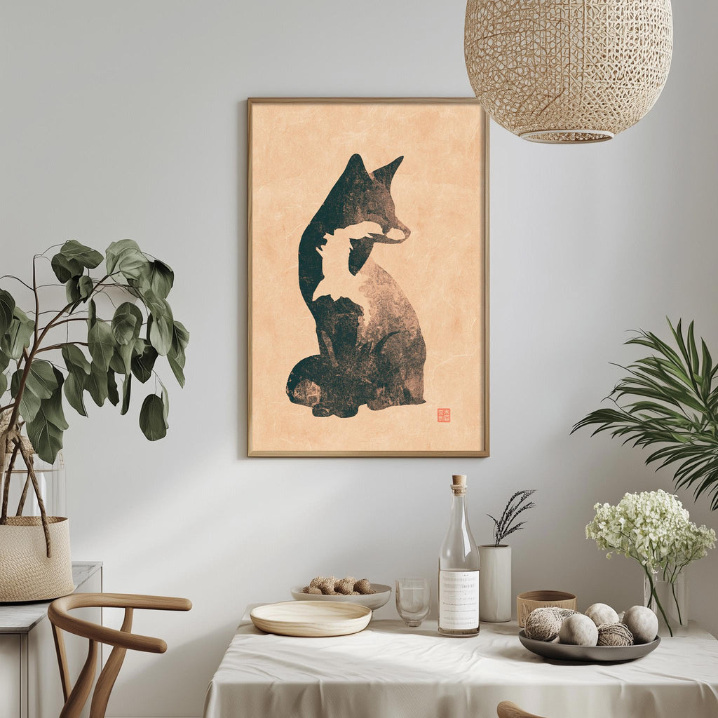 a dining table with a white tablecloth, a bowl of fruit, a bottle, and a vase with flowers. Above the table, there is a framed picture of a cat.