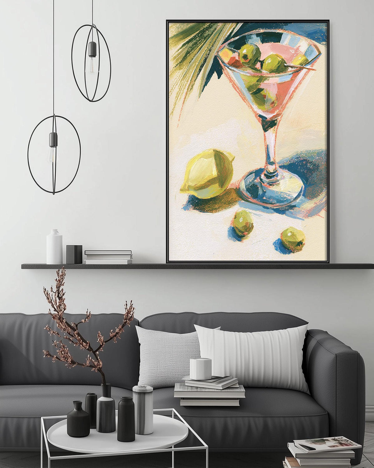 a living room with a gray sofa, a coffee table, and a large framed painting of a martini glass with olives and a lemon on the wall above it.