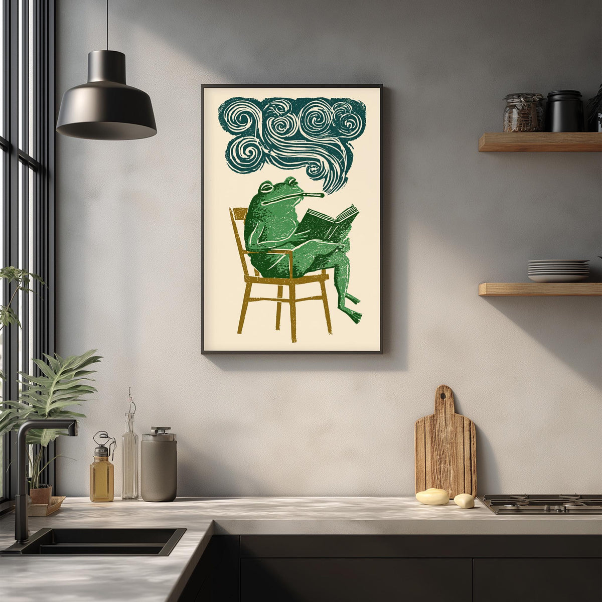 a framed illustration of a green frog sitting in a chair and reading a book, with a cloud-like shape above the frog's head.