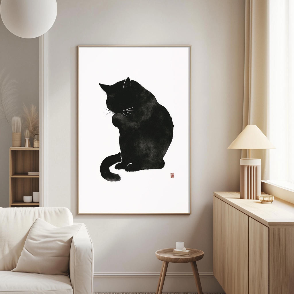 a black cat sitting on a white wall, with a framed print of the cat as the focal point.