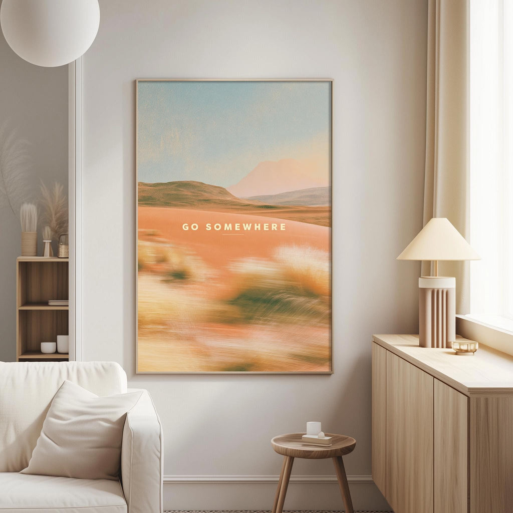 a large framed poster with the text "GO SOMEWHERE" hanging on a wall in a living room setting.