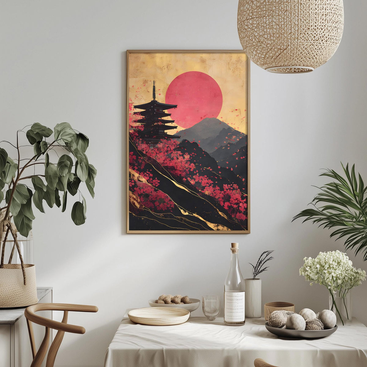a dining table with a white tablecloth, a bottle, a bowl, and a vase with flowers. Above the table, there is a framed picture of a pagoda with a red sun in the background.