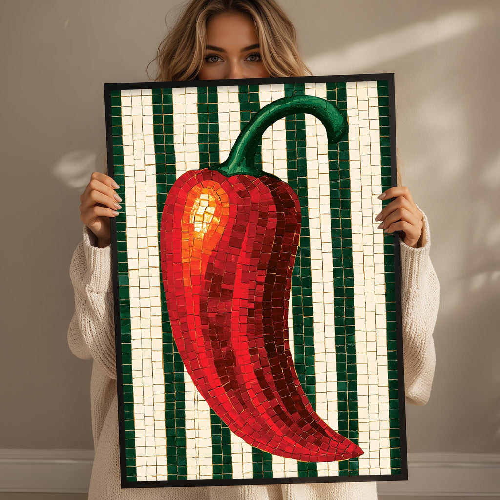 A woman holds up a framed mosaic of a red pepper, with green and white stripes.