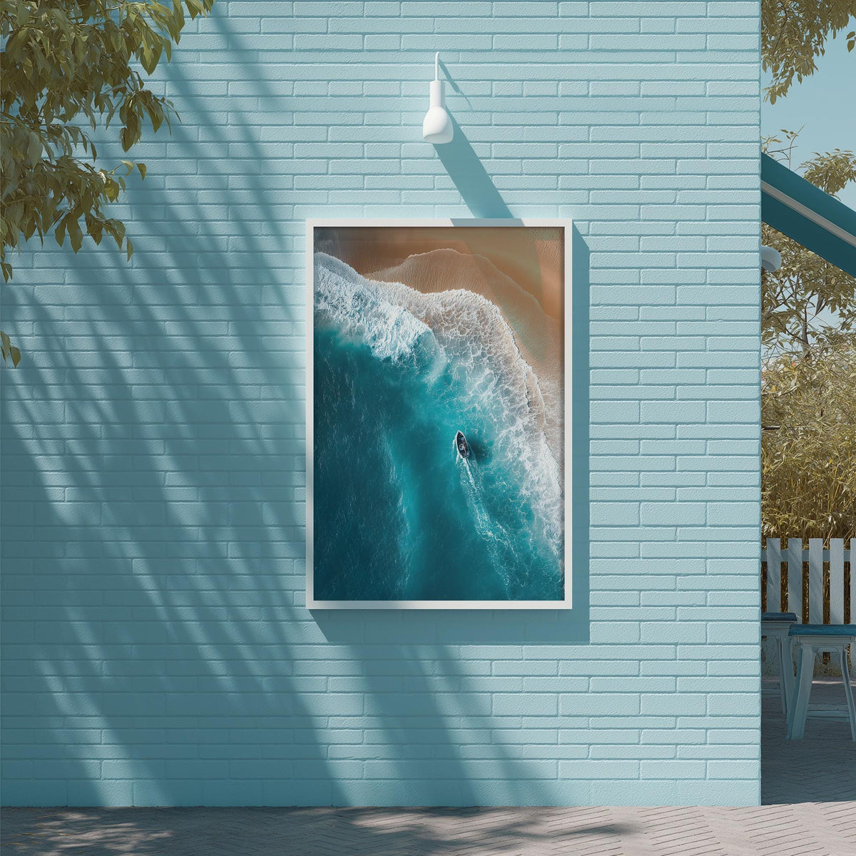 a serene beach scene with a surfer riding a wave in the ocean. The surfer is positioned in the center of the frame, with the wave curling around them. The backdrop is a light blue wall, and there is a white light fixture hanging above the picture.
