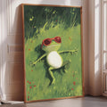A framed painting of a green frog wearing red sunglasses, lying on a grassy field with flowers.