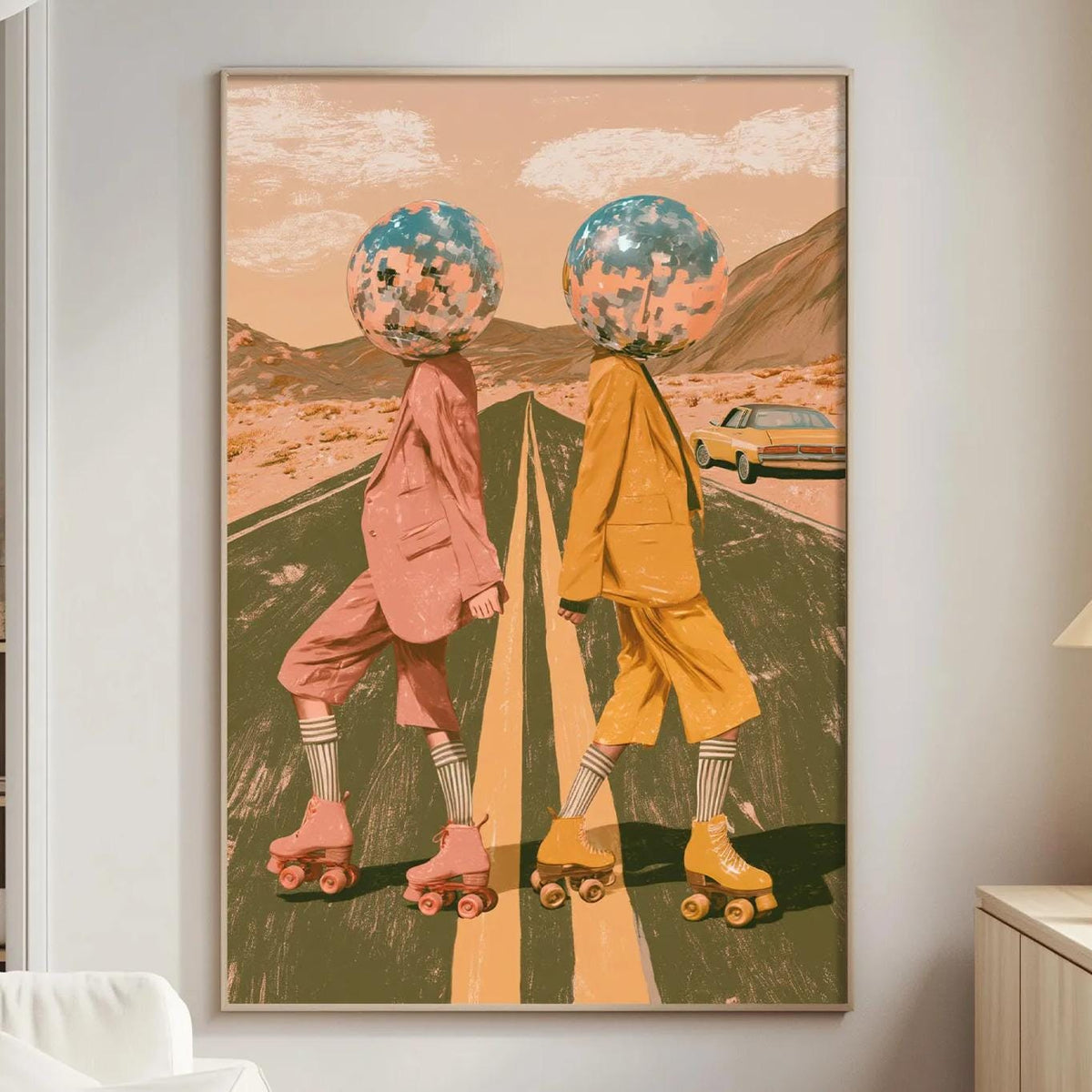 a large framed artwork depicting two people on rollerblades, with one person wearing a pink outfit and the other wearing a yellow outfit, set against a desert landscape with mountains in the background.