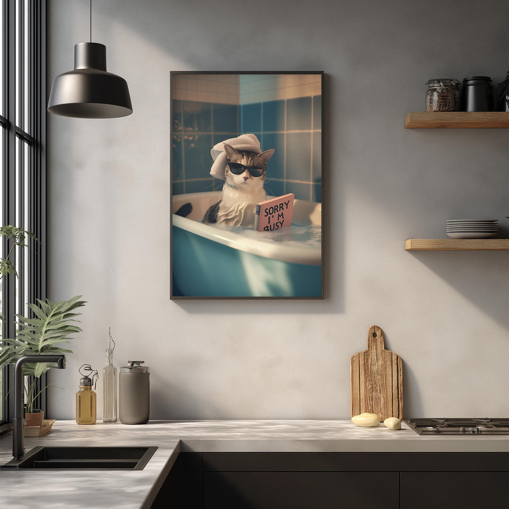 A framed image of a cat sitting in a bathtub, wearing sunglasses and holding a sign that says "I'm sorry". The cat appears to be looking out of the tub, with a kitchen counter and various kitchen items visible in the background.