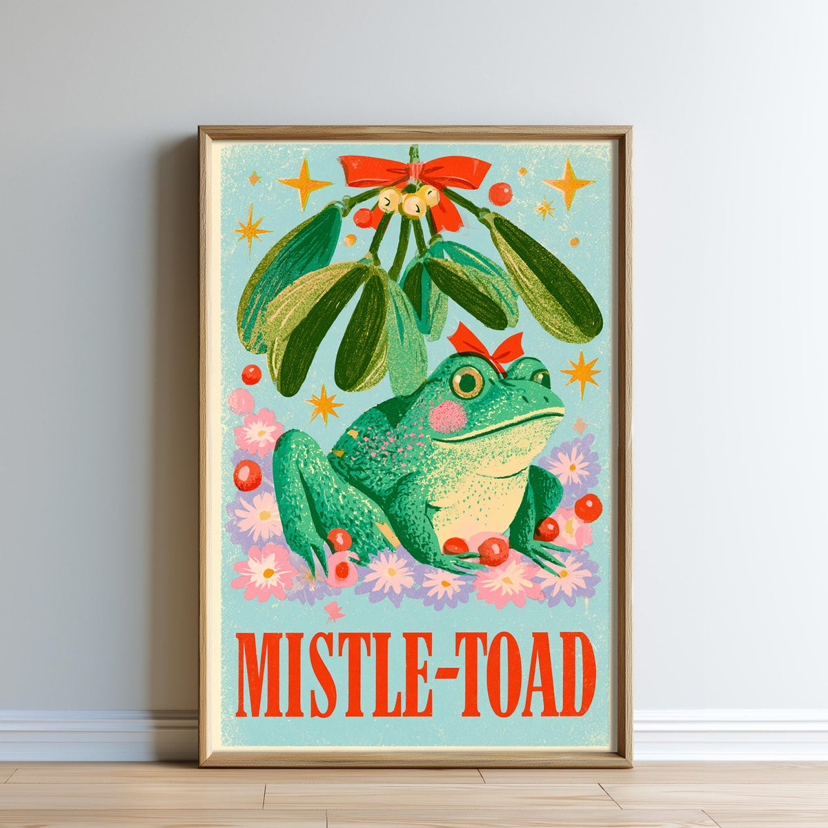 The image is a framed poster featuring a green frog sitting under a mistletoe plant, surrounded by flowers and stars.
