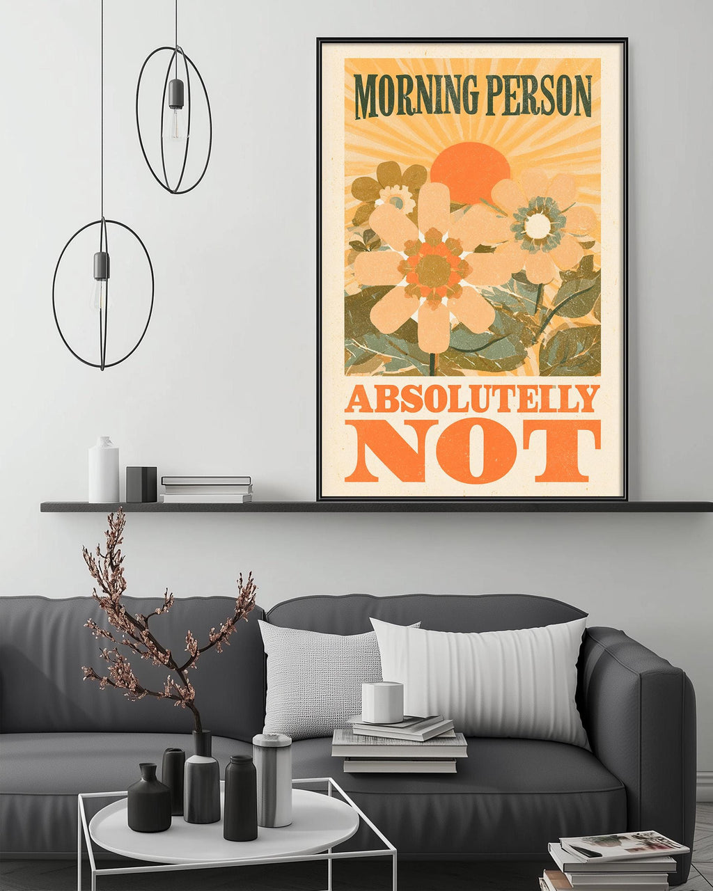a poster with the text "MORNING PERSON ABSOLUTELY NOT" displayed on a wall above a gray couch with decorative items on it.