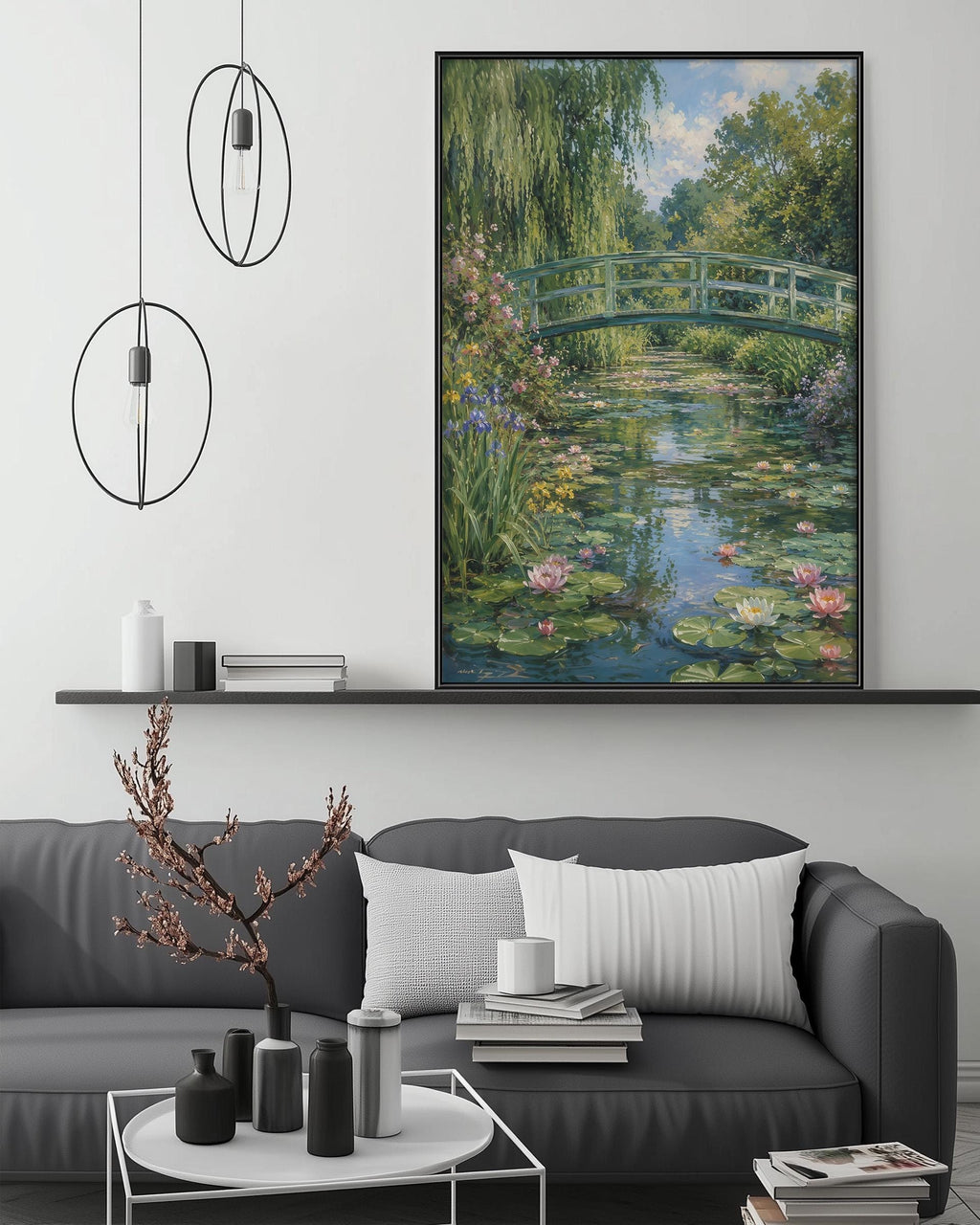 a large painting of a serene pond with a bridge, surrounded by lush greenery and pink flowers, hanging on a wall above a gray couch with a coffee table in front of it.