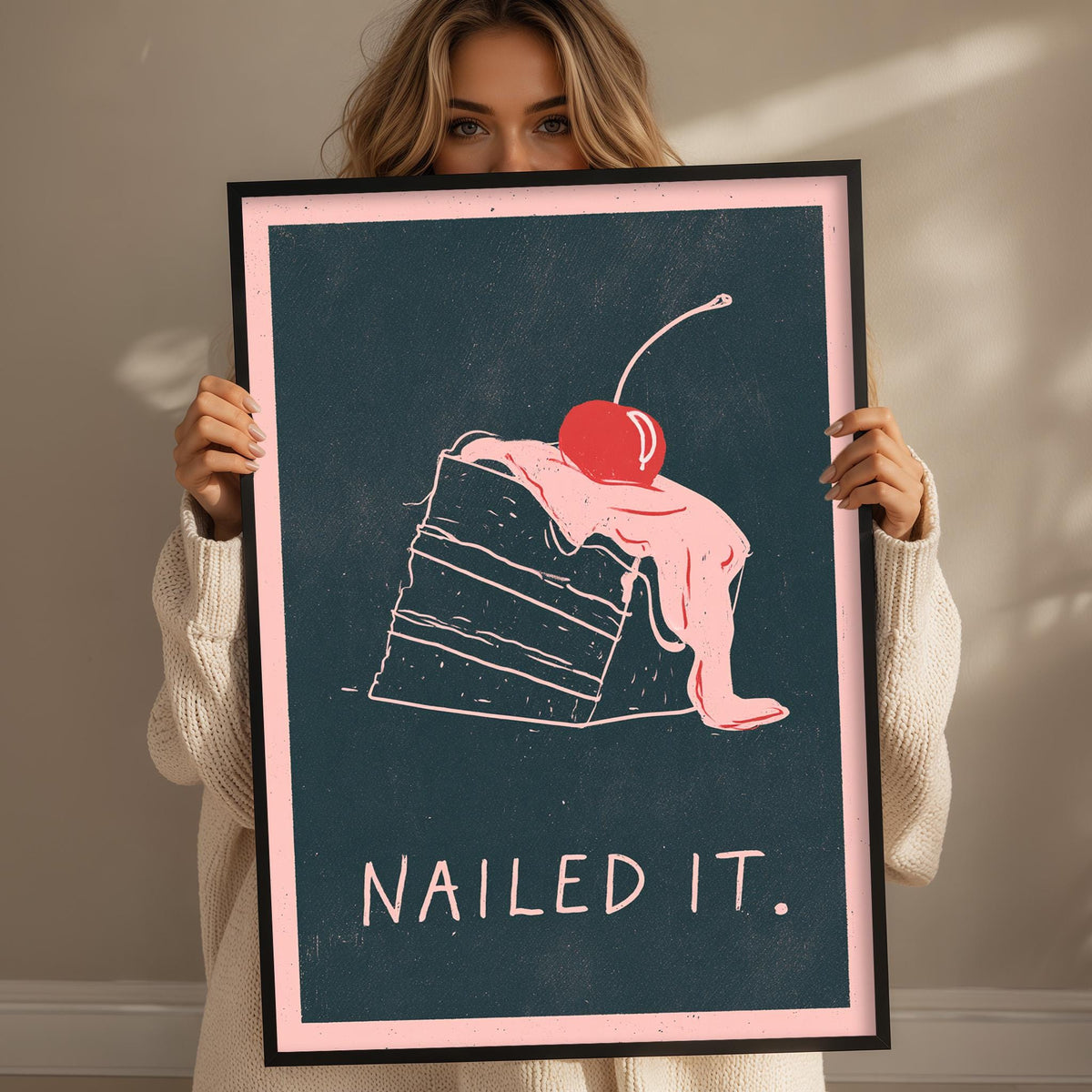 A woman holding a framed poster with a drawing of a slice of cake and the text "Nailed it."