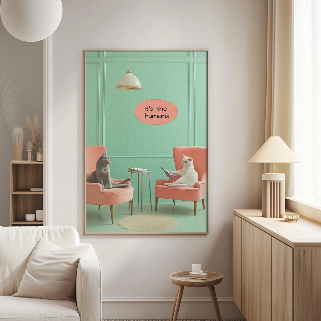 two cats sitting in chairs, with one cat reading a book and the other cat looking at it. The text above the image says "It's the humans".