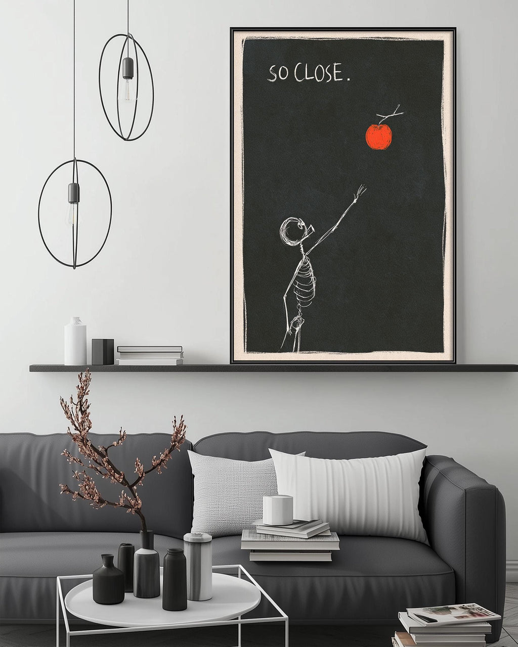 a living room with a gray sofa, a coffee table, and a framed artwork depicting a skeleton reaching for an orange.