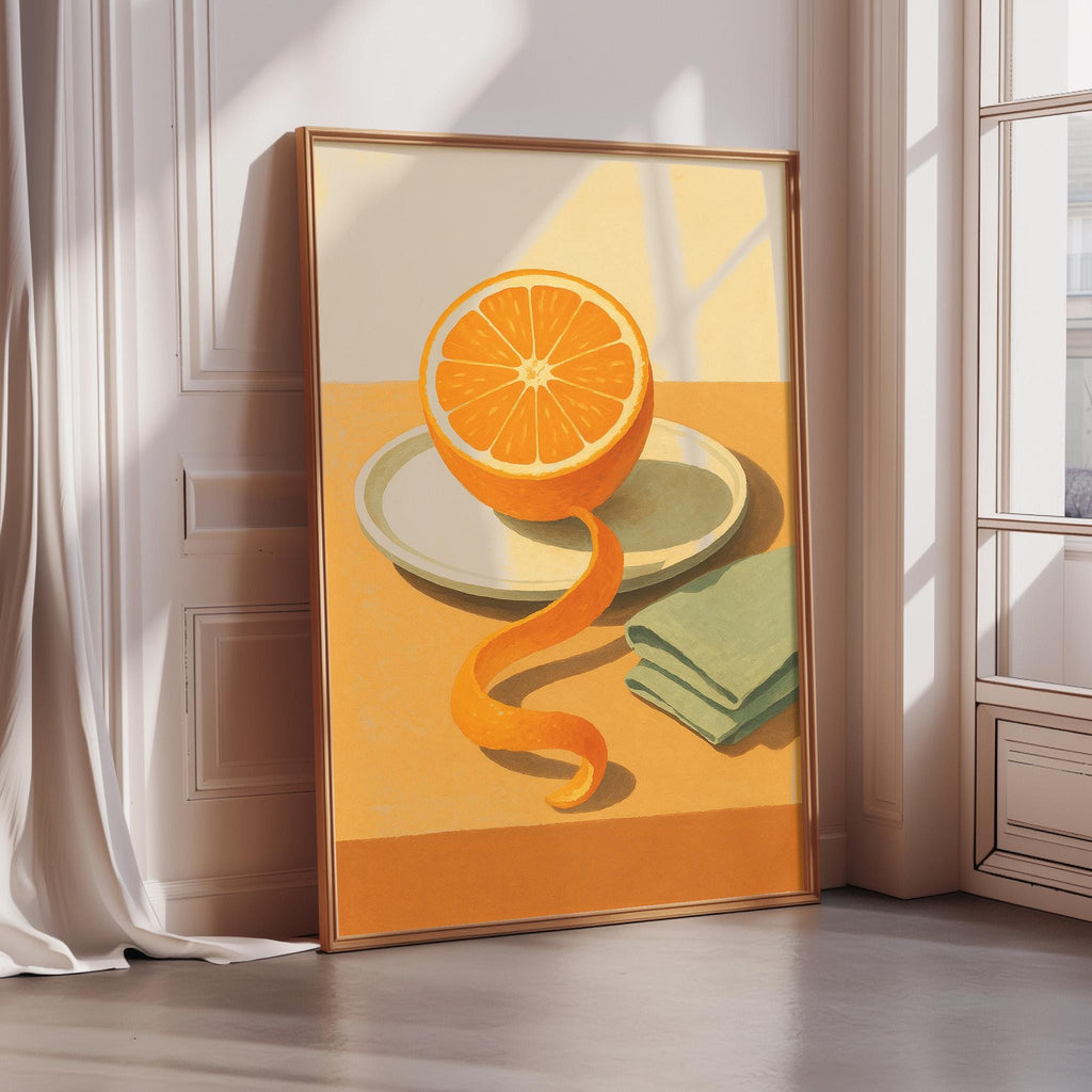 A framed painting depicting an orange slice on a table, with a green napkin and a folded towel nearby.