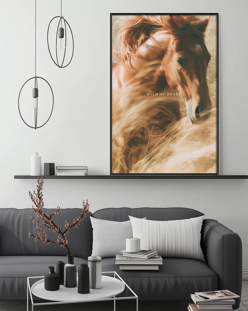 a large framed picture of a horse with the text "Wild at heart" above it, hanging on a wall above a gray couch with a coffee table in front of it.