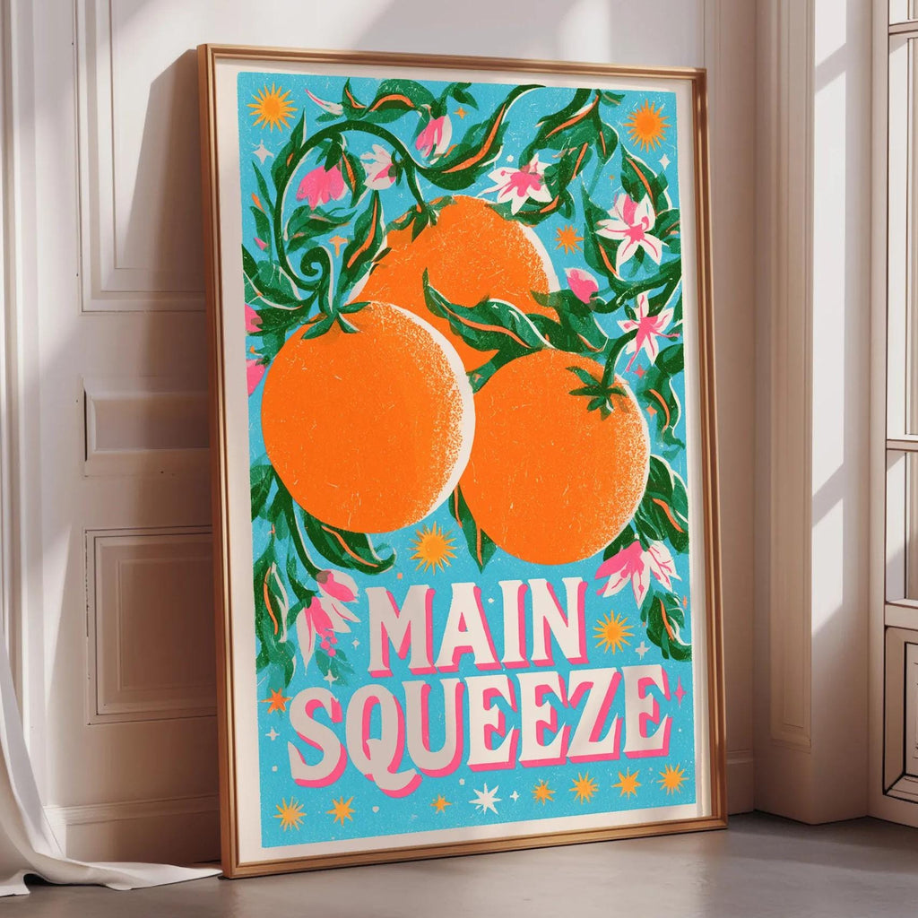 A framed poster with a vibrant illustration of oranges and flowers, along with the text "MAIN SQUEEZE" prominently displayed.