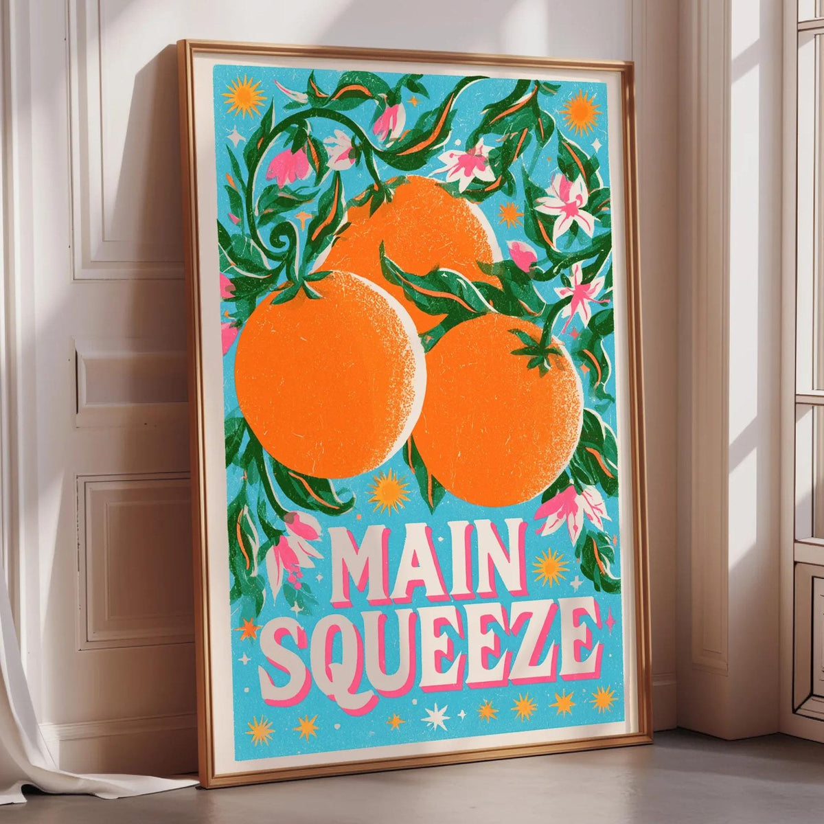 A framed poster with a vibrant illustration of oranges and flowers, along with the text "MAIN SQUEEZE" prominently displayed.
