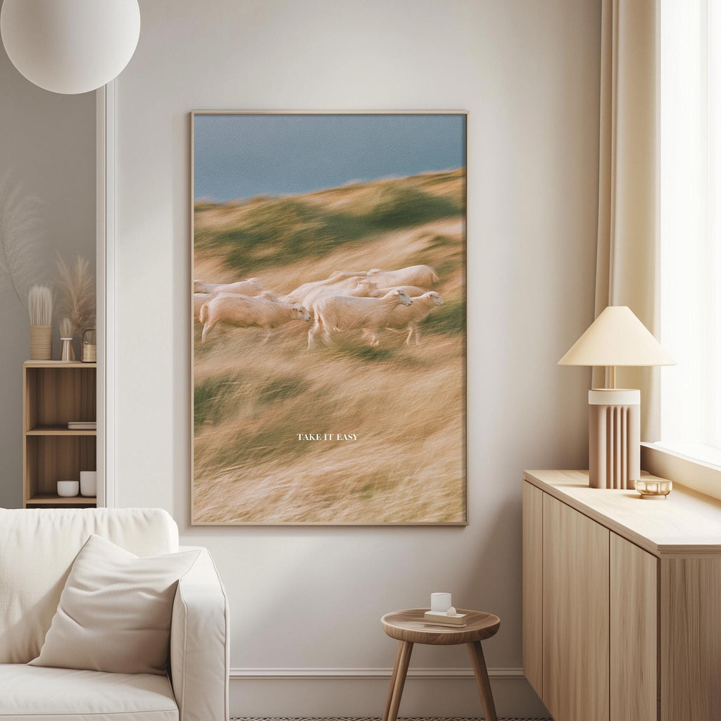 a large framed picture of a herd of sheep in a field, hanging on a wall in a living room.