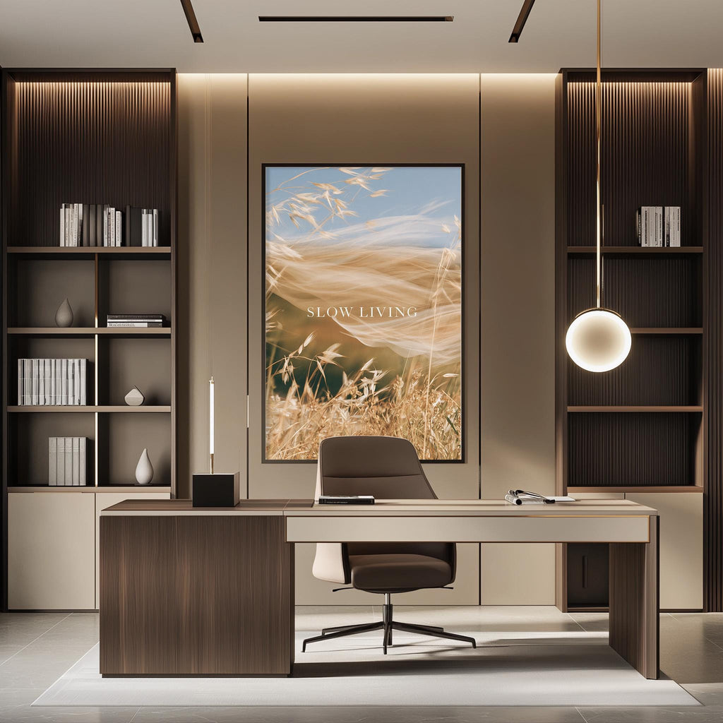 a modern and minimalist office space with a large framed artwork of wheat fields on the wall, a wooden desk with a chair, and built-in bookshelves.