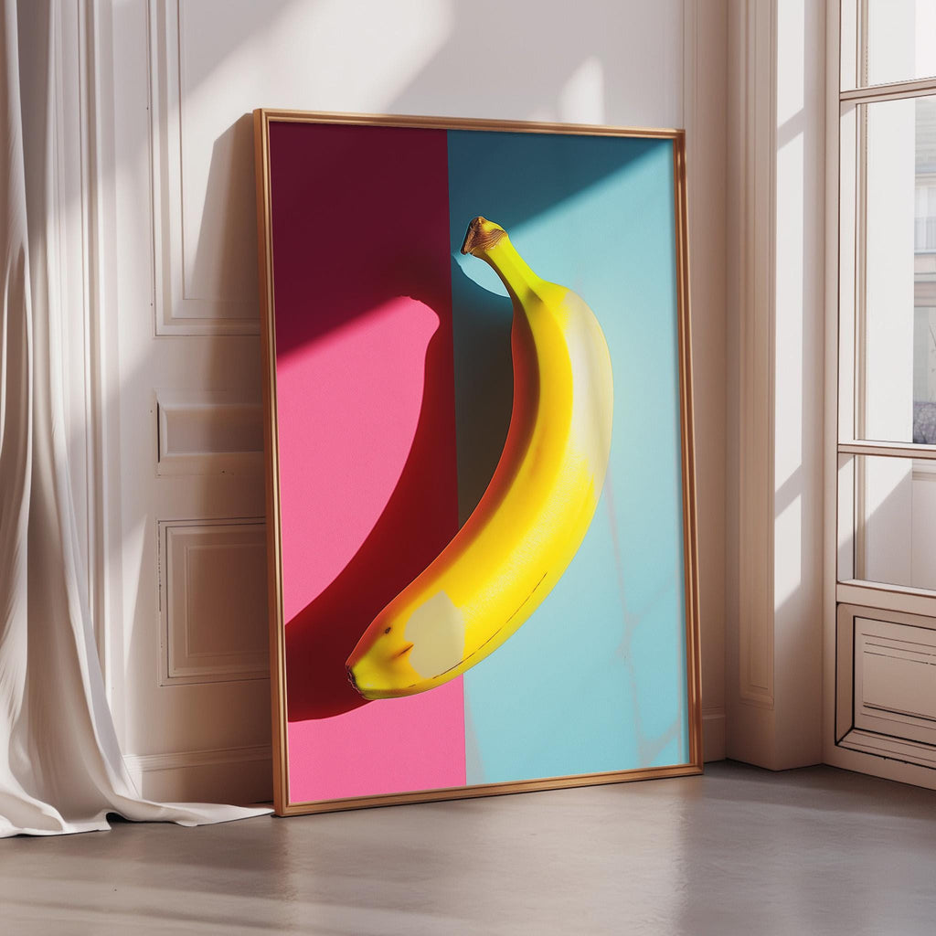 A framed artwork depicting a yellow banana against a vibrant background of pink and blue.