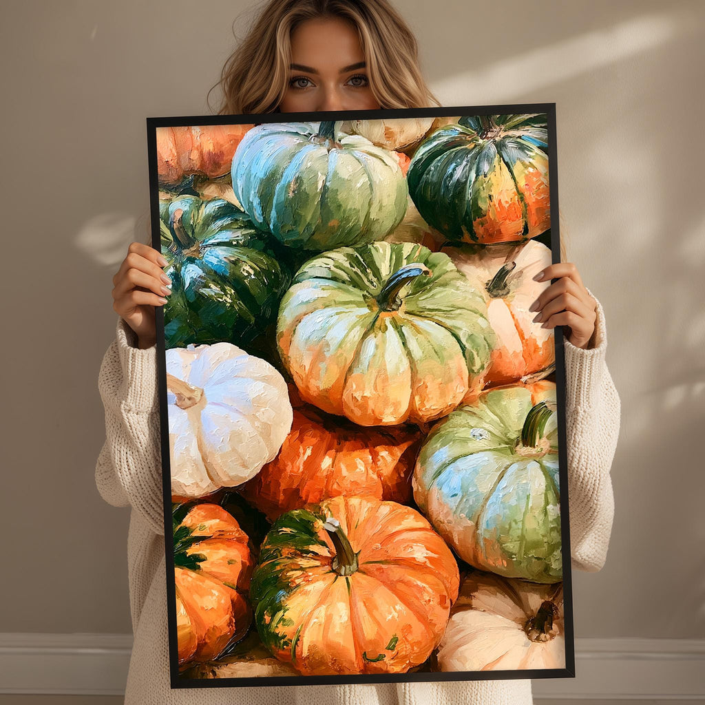 A woman holds up a framed print of a vibrant collection of pumpkins, showcasing a variety of colors and sizes.