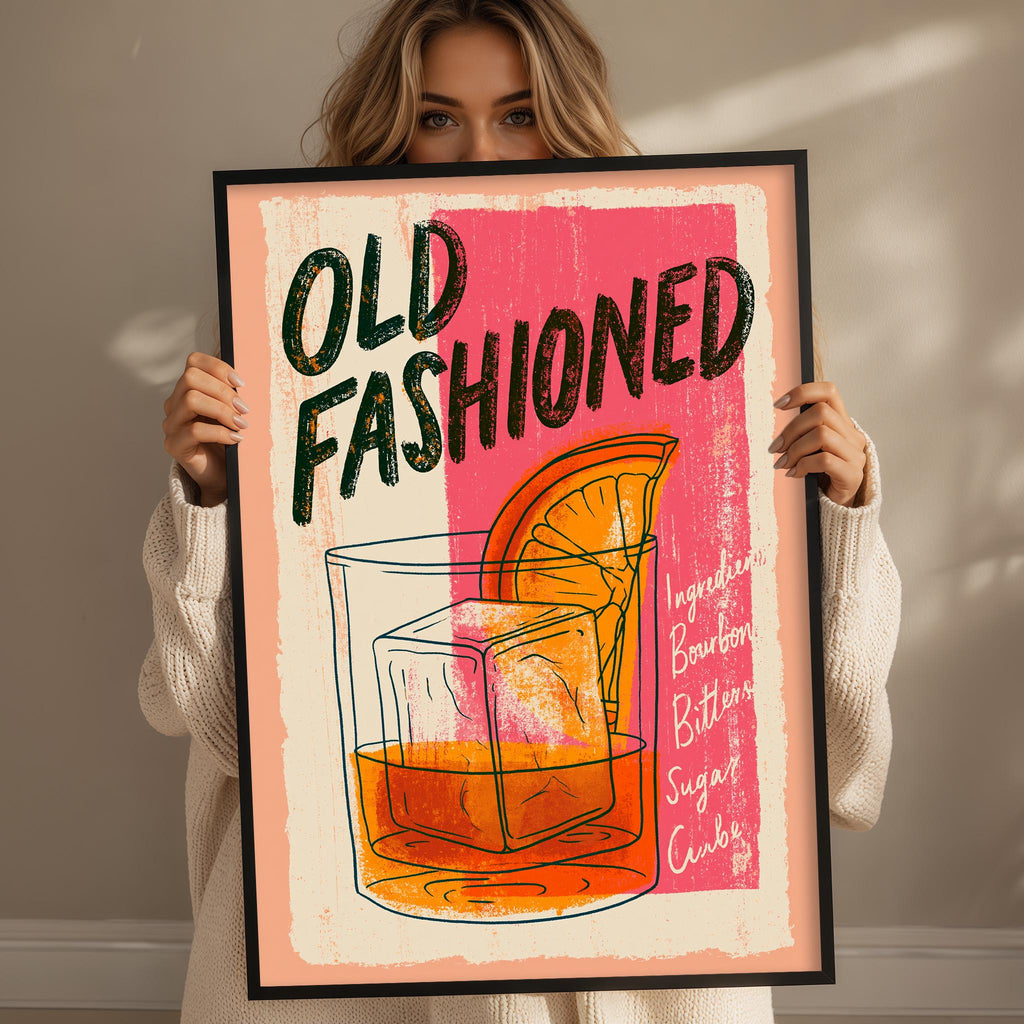 A woman holding a framed poster with a colorful illustration of a cocktail glass and a slice of orange.