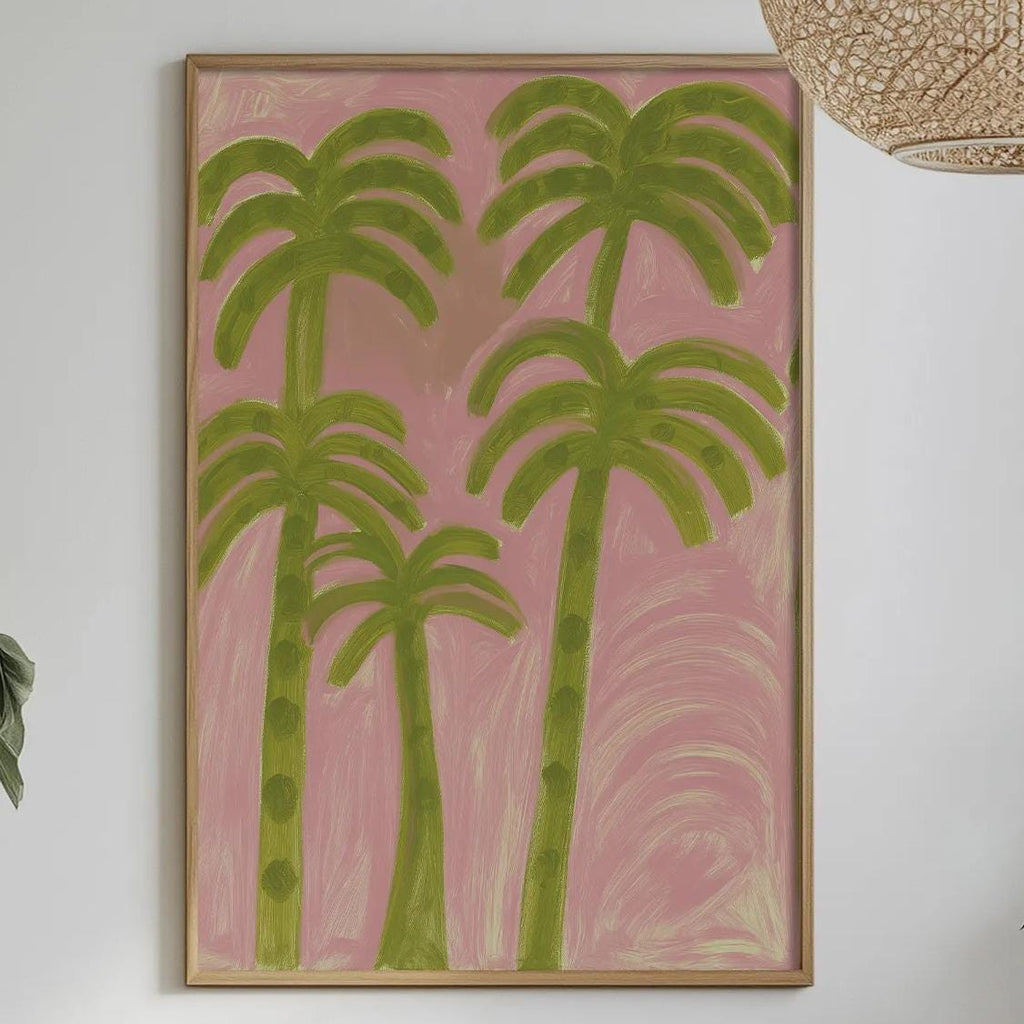 a dining table with a white tablecloth, a bowl of fruit, a bottle, and a vase with flowers. Above the table, there is a framed painting of palm trees in a pink and green color scheme.