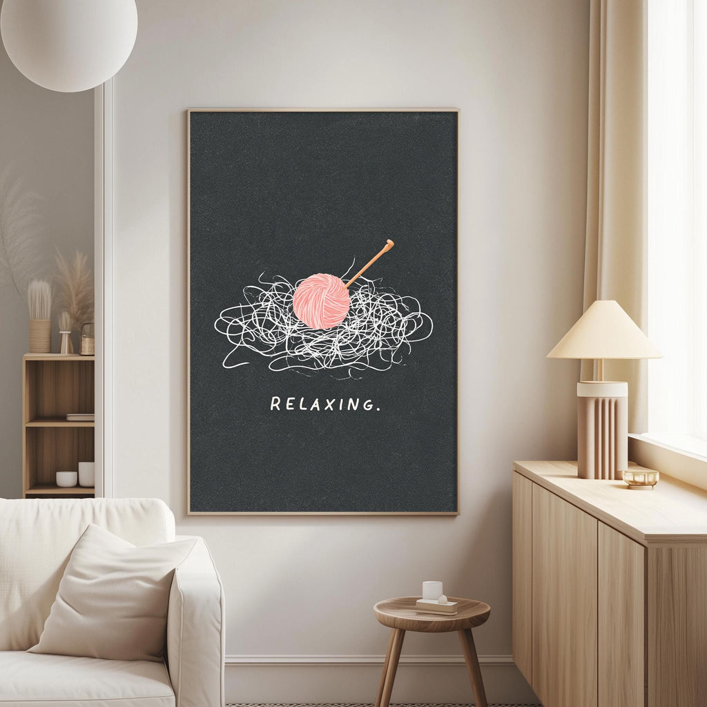 a cozy living room with a large black framed poster on the wall that says "Relaxing." The poster also includes a whimsical illustration of a ball of yarn and a crochet hook, adding a playful touch to the room's decor.