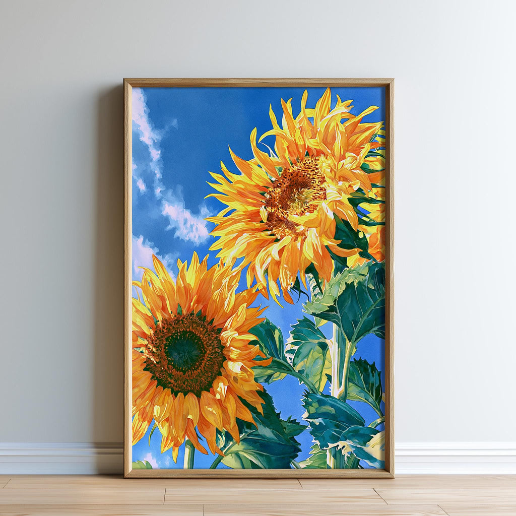 two large, vibrant sunflowers with yellow petals and green leaves, set against a blue sky with fluffy white clouds.