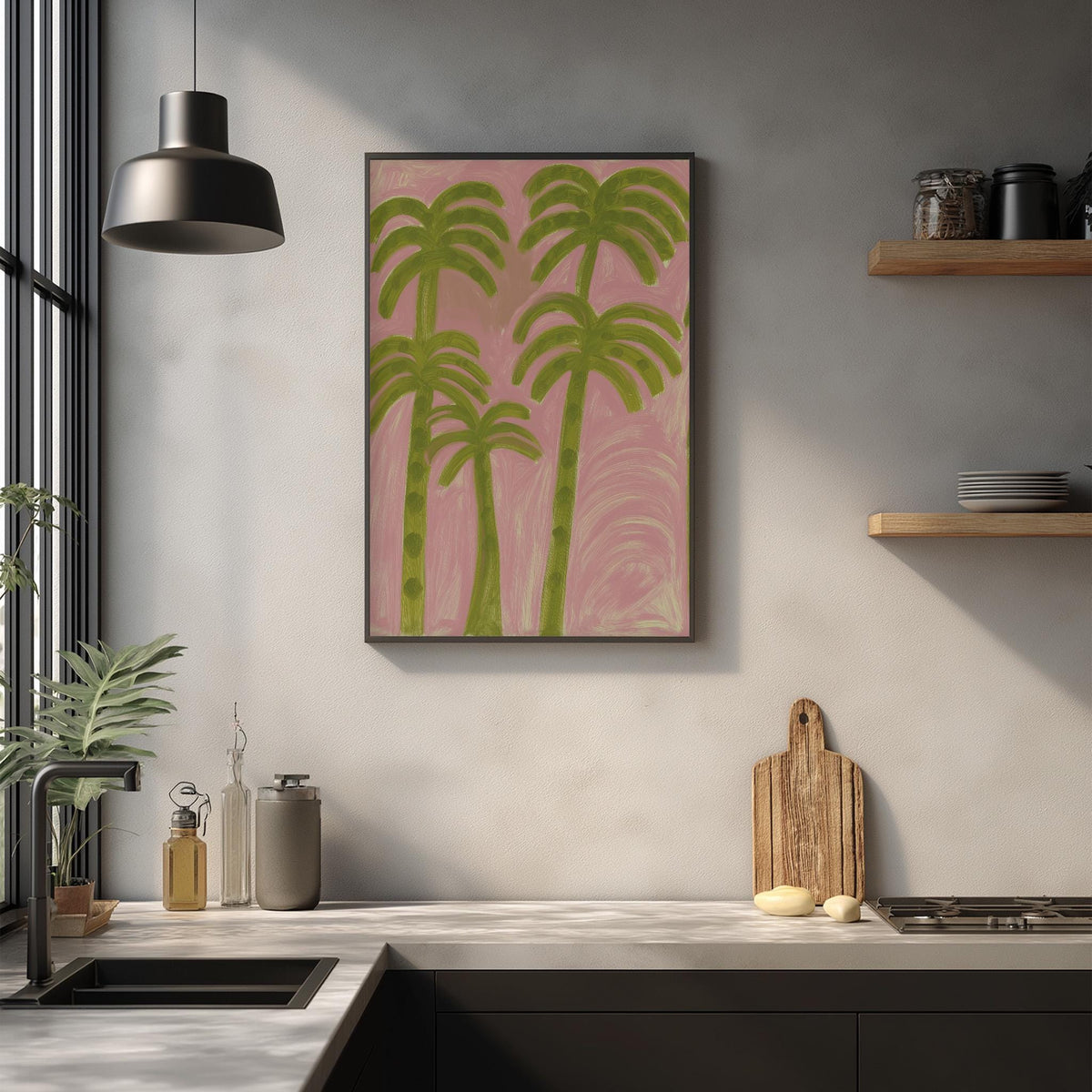 a kitchen counter with a framed painting of palm trees hanging above it. The painting has a pink background and green palm trees. On the counter, there are various kitchen items such as a cutting board, a knife, and a bottle. The kitchen also has a window and a shelf with dishes on it.