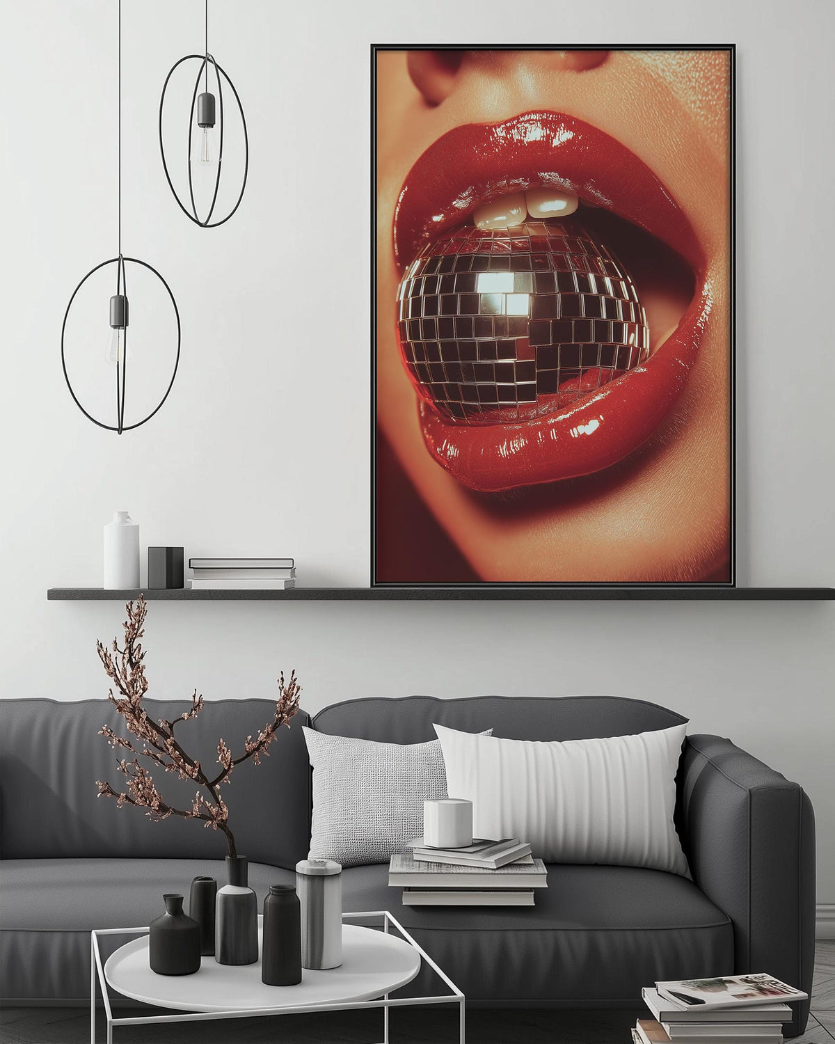 a large, vibrant, and glossy picture of a woman's lips with a disco ball in her mouth, hanging on a wall above a gray couch with a coffee table in front of it.