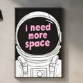 a kitchen counter with various kitchen items, such as a cutting board, a bottle, and a bowl. Above the counter, there is a framed poster with the text "I need more space" in pink letters.