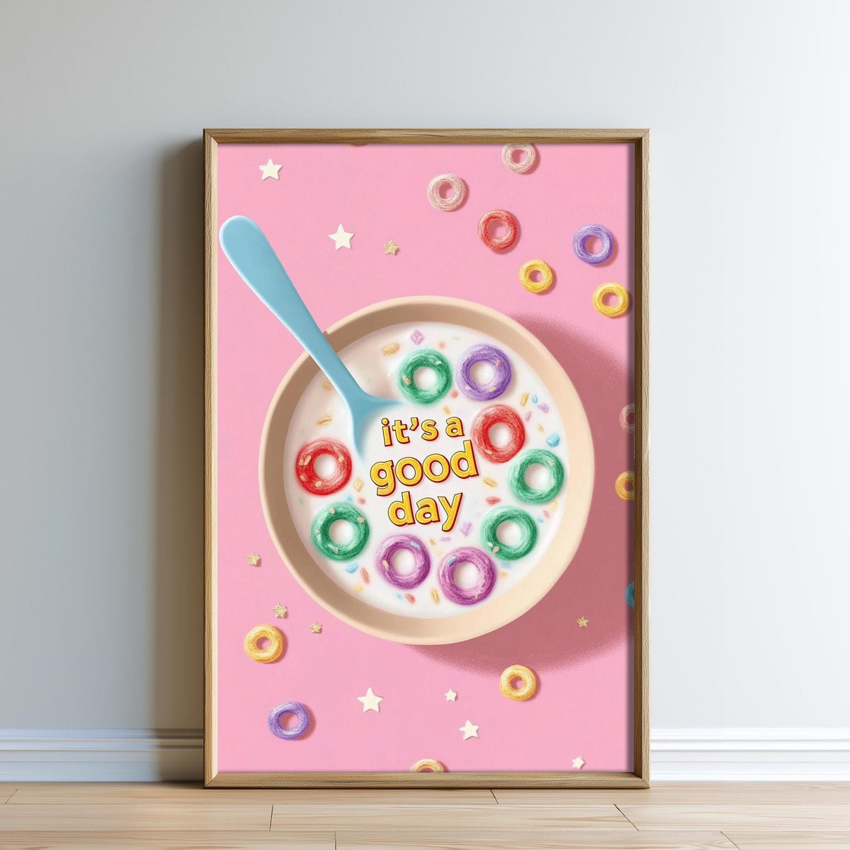 A framed poster with a pink background, featuring a bowl of cereal with colorful donuts and the text "It's a good day" written on it.