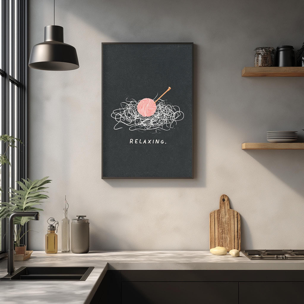 a kitchen counter with various items, including a wooden cutting board, a sink, and a potted plant. Above the counter, there is a framed poster with the text "Relaxing" and an illustration of a ball of yarn and a crochet hook.
