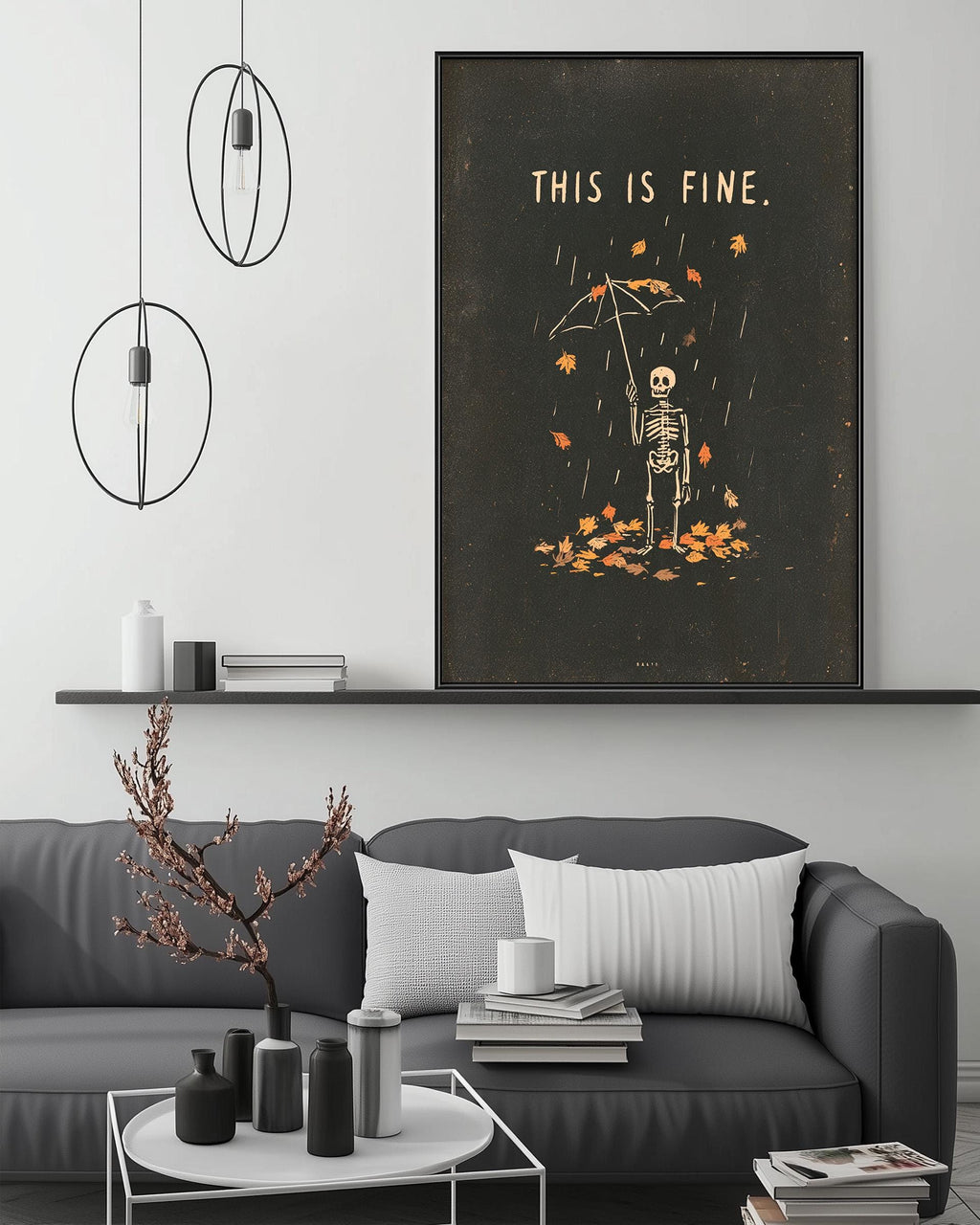 a living room with a gray sofa, a coffee table, and a large framed poster on the wall. The poster depicts a skeleton holding an umbrella and surrounded by falling leaves, with the text "THIS IS FINE."