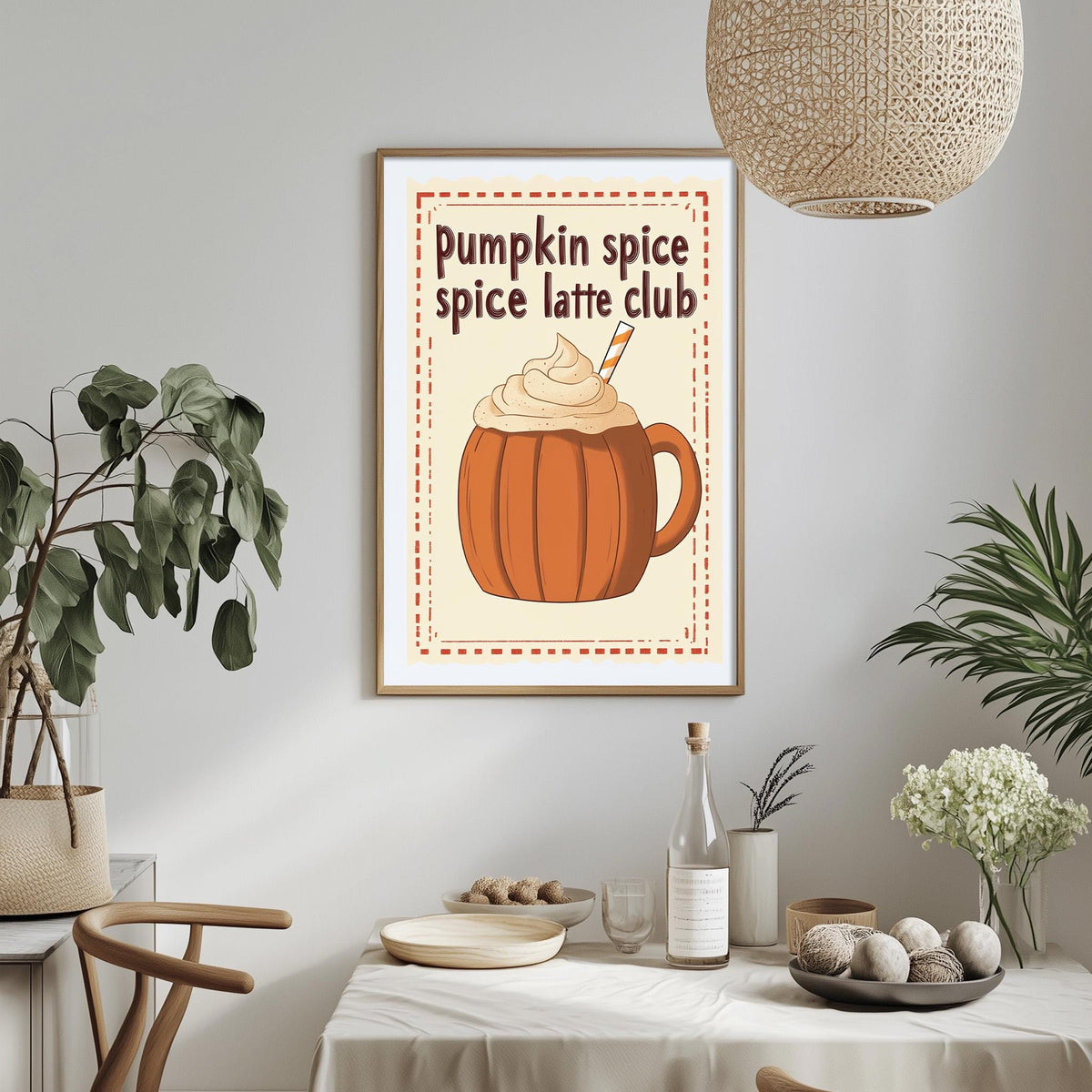 a framed poster of a pumpkin spice latte with whipped cream, hanging on a wall above a dining table with various items on it.