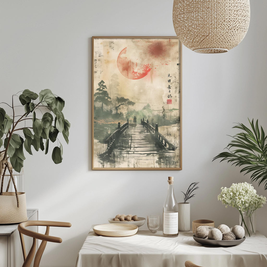 a dining table with a white tablecloth, a bottle, a bowl, and a vase with flowers. Above the table, there is a framed painting depicting a bridge leading to a red moon. The table is set with various items, including a wine glass, a plate, and a bowl. The room also has potted plants and a hanging light fixture, creating a cozy and inviting atmosphere.