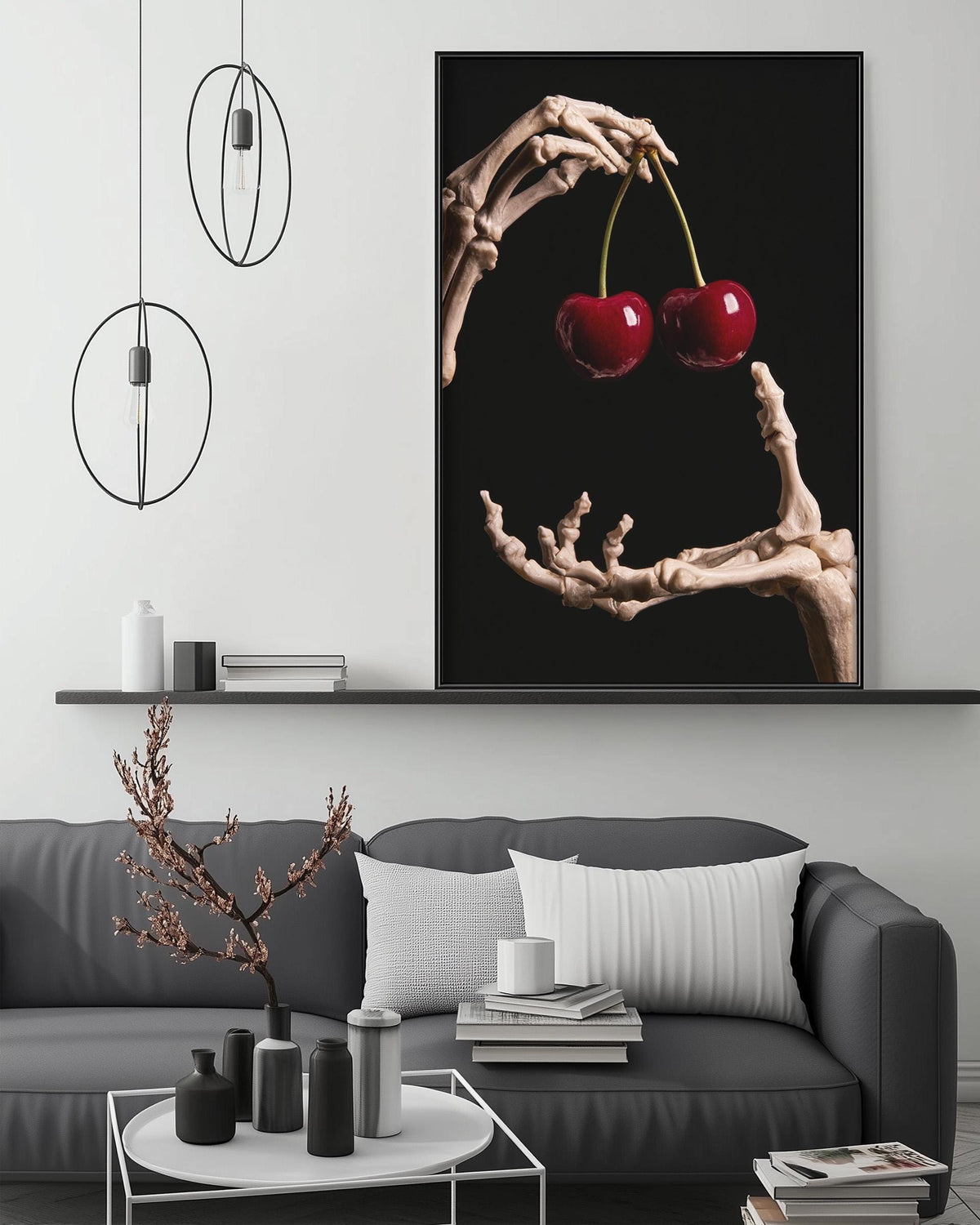 a black and white living room with a gray sofa, a coffee table, and a large framed artwork depicting a skeleton hand holding cherries.