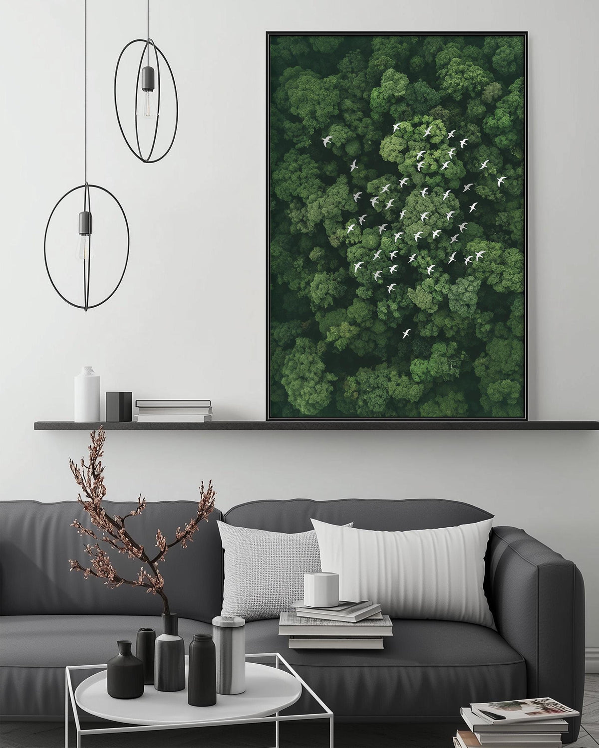 a modern living room with a gray sofa, a coffee table, and a large framed picture of a forest with birds flying above it. The room has a minimalist and clean design, with a black and white color scheme.
