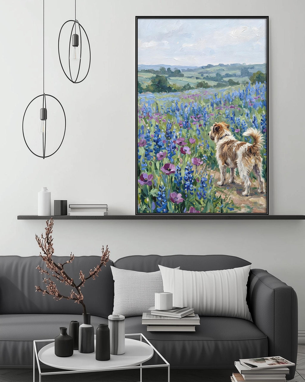 a large painting of a dog standing in a field of flowers, with a serene landscape in the background. The painting is hung on a wall above a gray couch, which has a coffee table in front of it. The room also includes a shelf with decorative items and a potted plant.