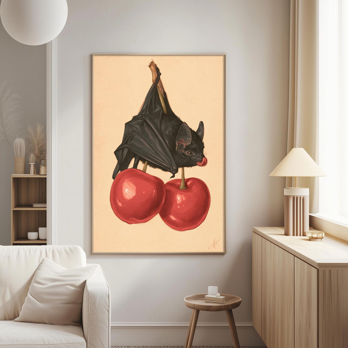 a framed painting of a bat perched on two red cherries, hanging on a wall in a living room setting.