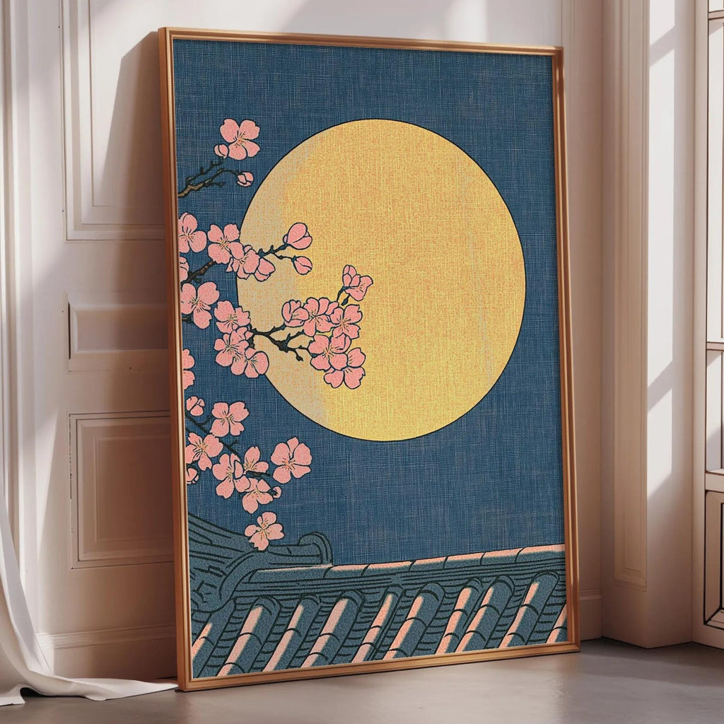 A framed artwork depicting a night scene with a large yellow moon and pink cherry blossoms against a dark blue background.
