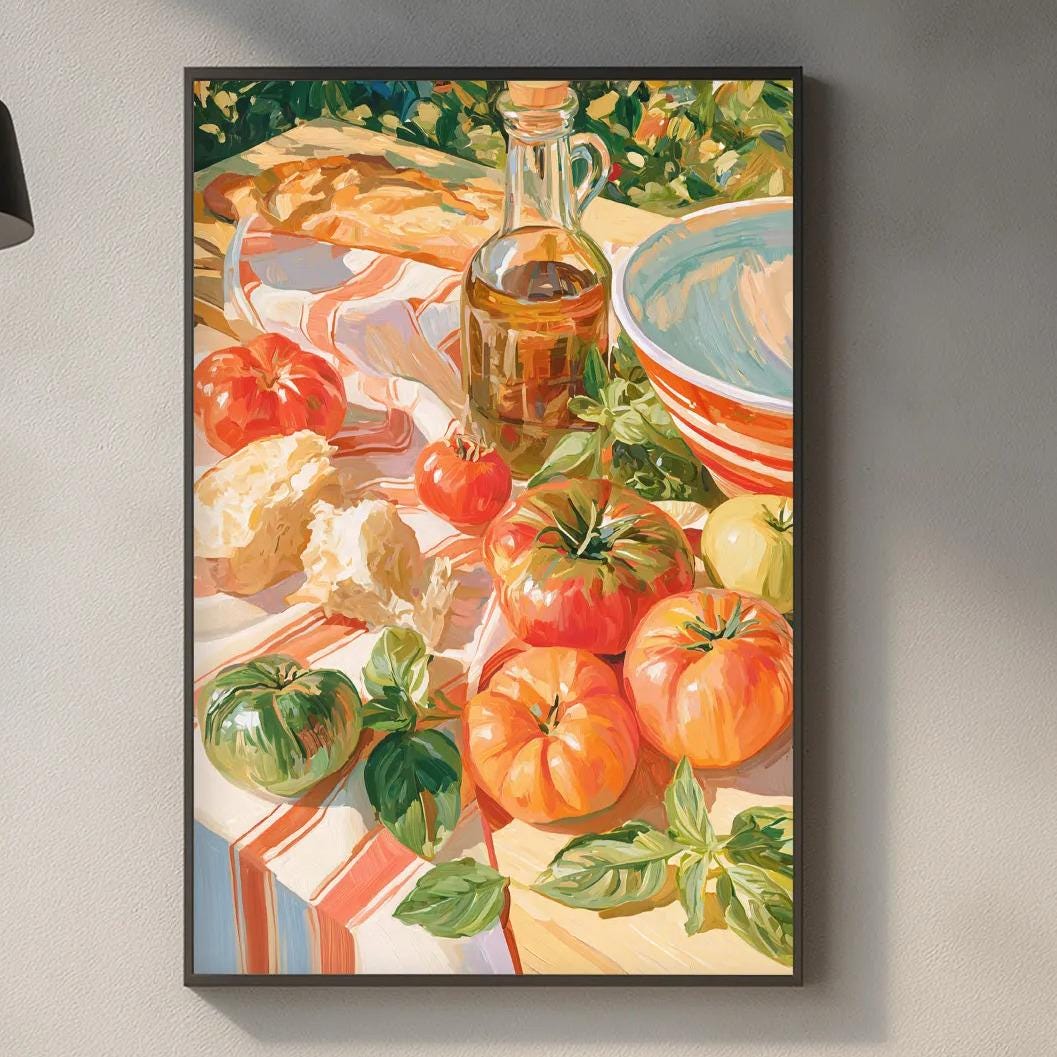 a kitchen counter with various kitchen items, including a cutting board, a bottle, and a bowl. Above the counter, there is a framed painting depicting a table with food, including tomatoes, bread, and other dishes.