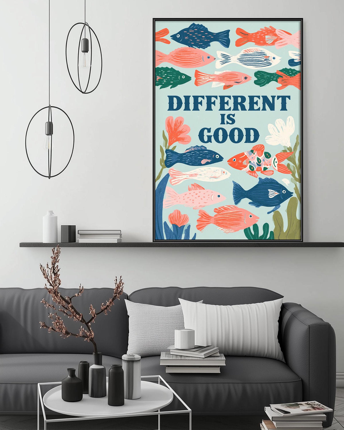 a living room with a gray couch, a coffee table, and a framed poster of colorful fish above it. The poster has the text "DIFFERENT IS GOOD" written on it.