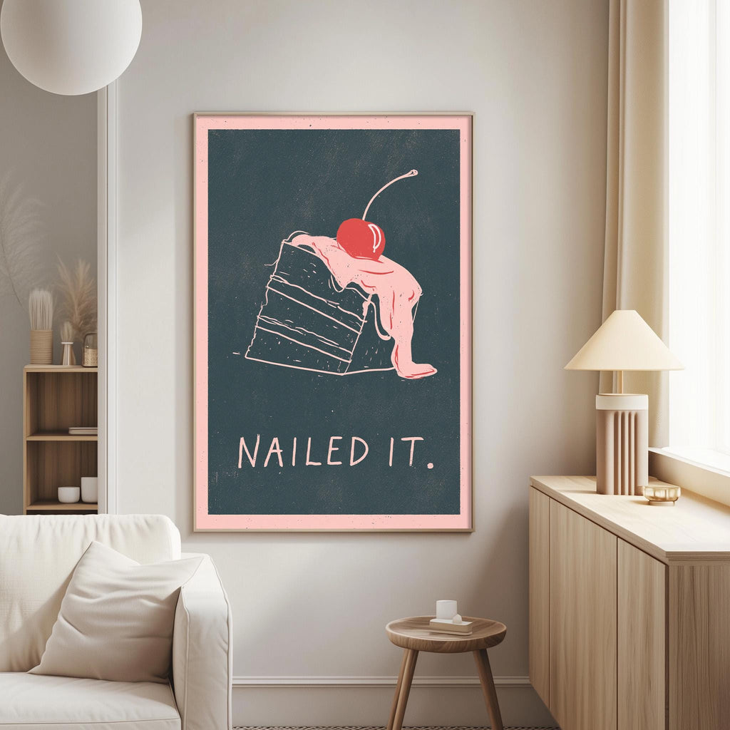 a framed poster with a whimsical illustration of a cake with a cherry on top, accompanied by the text "Nailed it."