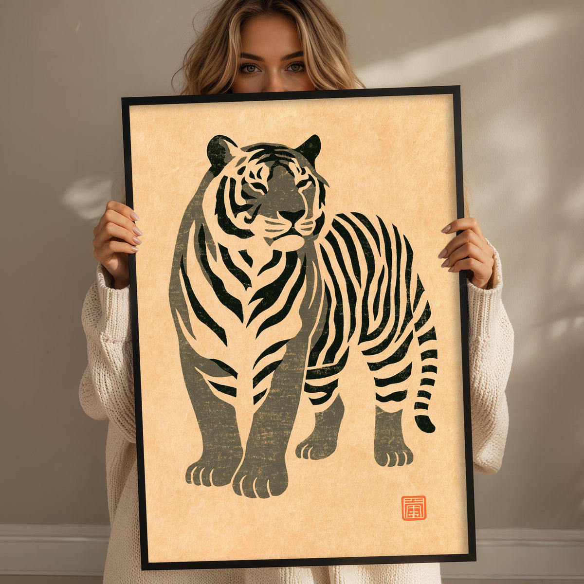 A woman is holding up a framed print of a stylized tiger illustration.